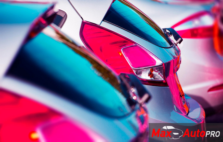 Close-up image of tail lights of three cars sitting on a car lot